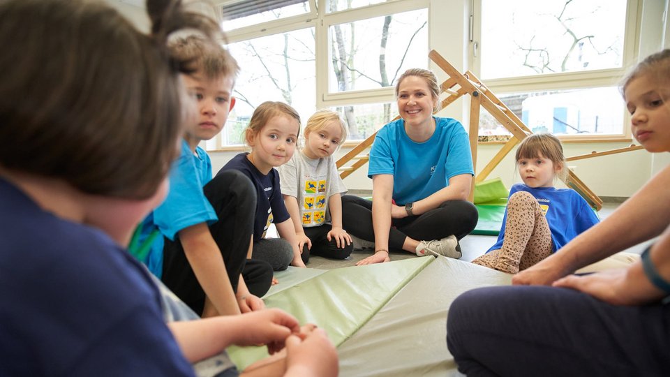 Das Bild zeigt die Erzieherin Anja Korte im Kreis von Kindergartenkindern