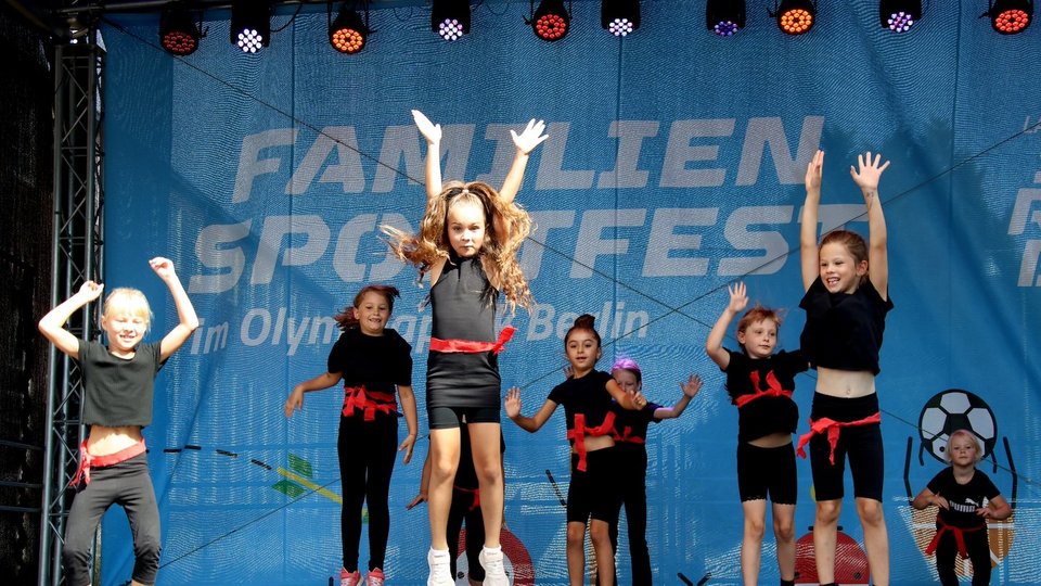 Das Foto zeigt hüpfende Kinder auf der Bühne des Familiensportfests im Olympiapark 2024