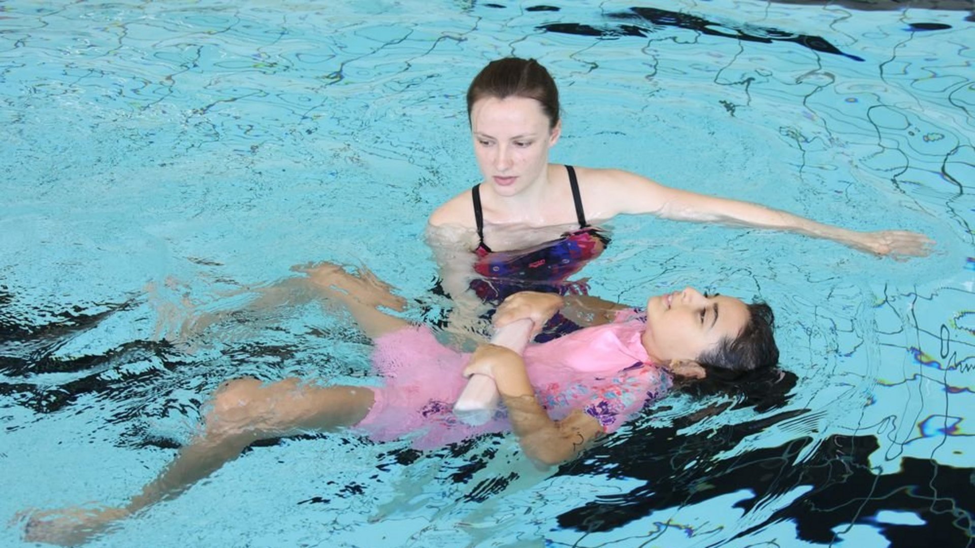 Schwimmlehrerin mit Schwimmschülerin im Wasser